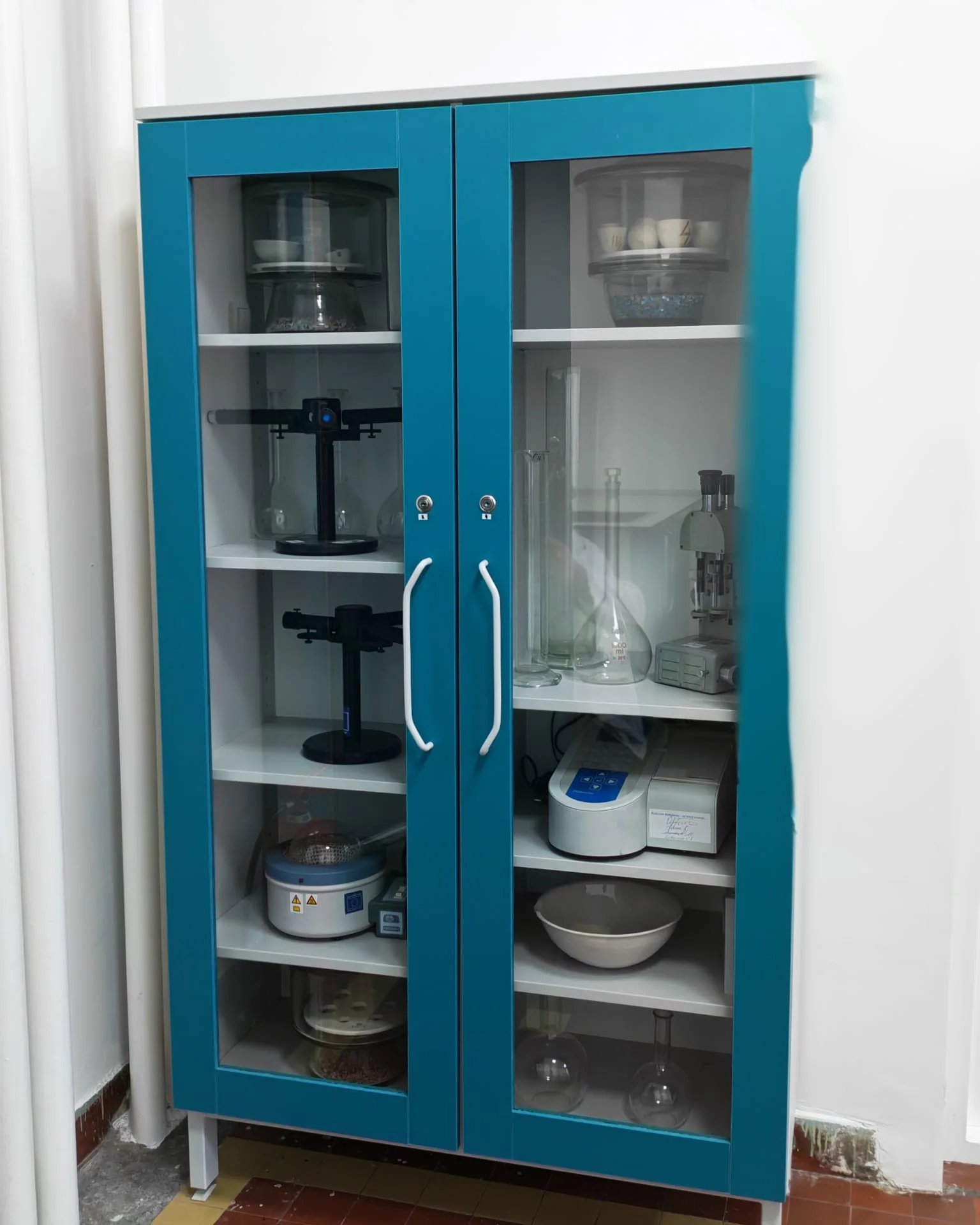 Стаклена витрина са лабораторијским посуђем и инструментима у лабораторији