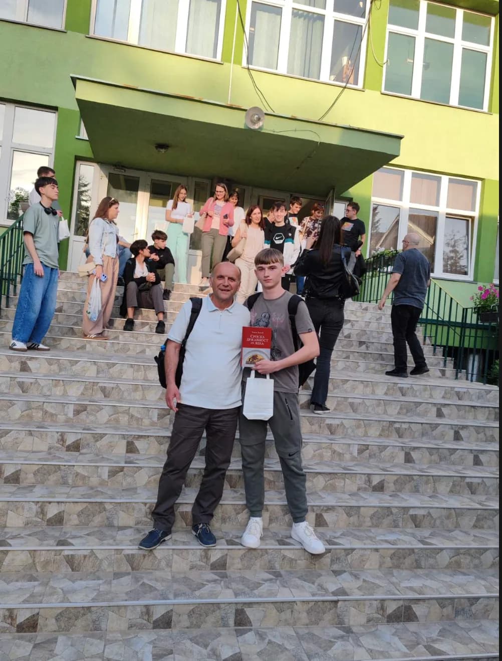 Радослав Чечур и професор Витимир Вита Станковић на степеништу након проглашења победника Републичког такмичења из историје -- ученик држи књигу „Српска државност 19. века“